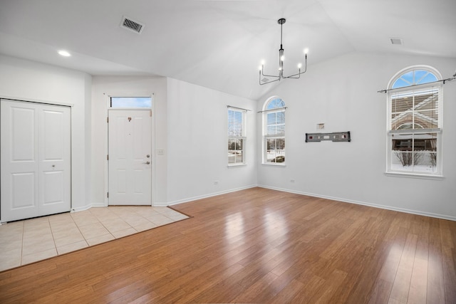 foyer featuring light wood-type flooring, a healthy amount of sunlight, a chandelier, and vaulted ceiling