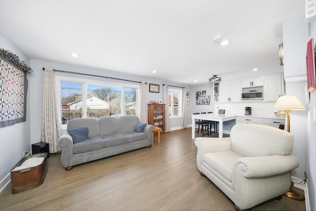 living room with baseboards, light wood-type flooring, and recessed lighting