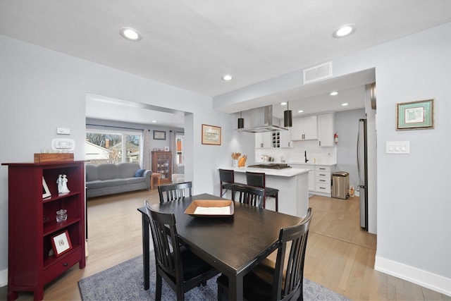 dining room with baseboards, light wood-style flooring, visible vents, and recessed lighting