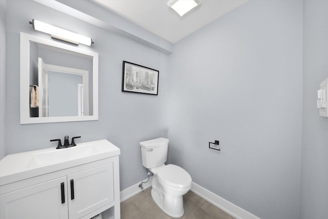 half bathroom featuring toilet, tile patterned flooring, baseboards, and vanity