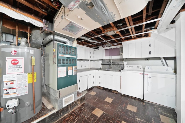 washroom with water heater, dark floors, washer and clothes dryer, and cabinet space