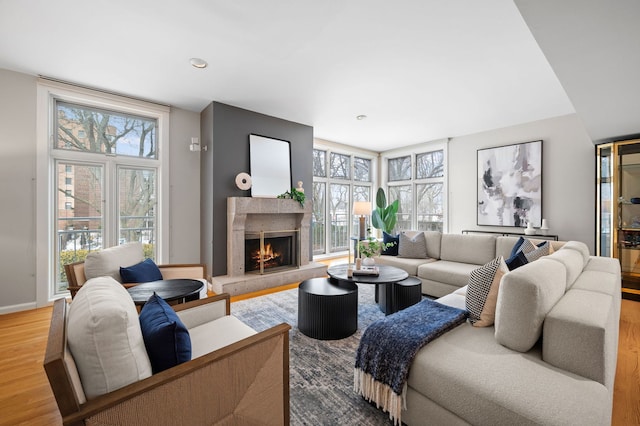 living area with baseboards, wood finished floors, a high end fireplace, and a healthy amount of sunlight