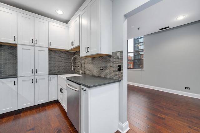 kitchen with dark wood finished floors, a sink, stainless steel dishwasher, dark countertops, and backsplash