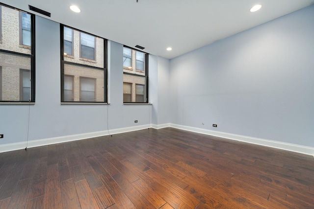 empty room featuring recessed lighting, baseboards, and dark wood-style floors