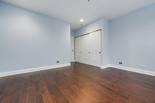 unfurnished bedroom with a closet, recessed lighting, baseboards, and dark wood-style flooring