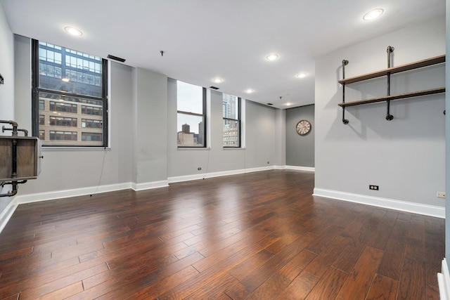 unfurnished living room featuring recessed lighting, wood finished floors, and baseboards