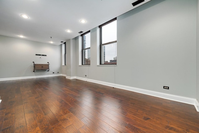 unfurnished room with dark wood finished floors, visible vents, recessed lighting, and baseboards