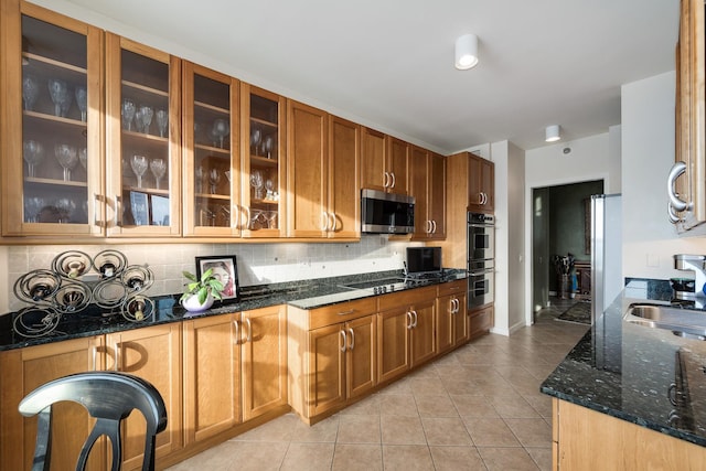 501 N Clinton St Unit 1705, Chicago, IL 60654 - kitchen with appliances with stainless steel finishes, light tile patterned floors, tasteful backsplash, dark stone countertops, and brown cabinetry