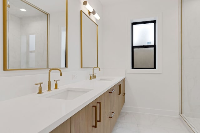 bathroom with marble finish floor, double vanity, a sink, and baseboards