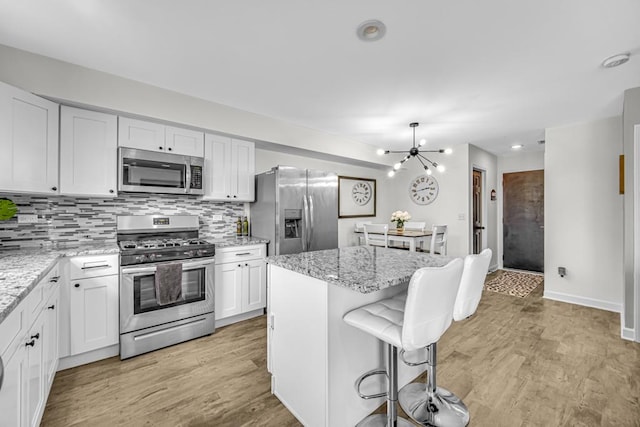 kitchen featuring white cabinetry, a kitchen island, light stone counters, and stainless steel appliances