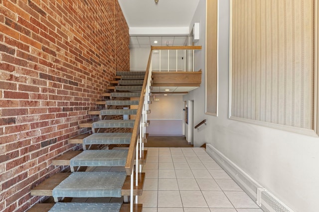 stairway featuring brick wall and tile patterned floors