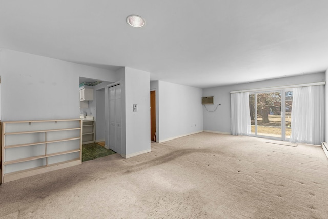 unfurnished living room featuring carpet floors, a wall mounted air conditioner, and baseboards