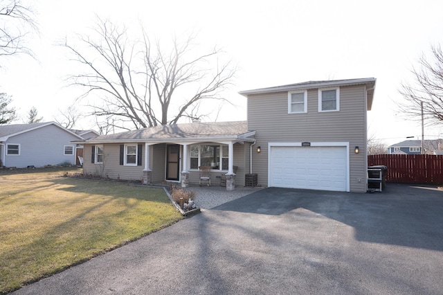 traditional-style house with a porch, an attached garage, a front yard, fence, and driveway