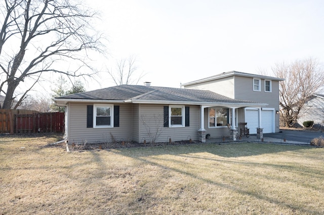 traditional-style home featuring aphalt driveway, a garage, fence, roof with shingles, and a front lawn