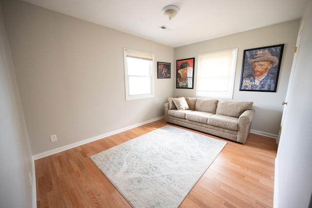 living room featuring light wood-type flooring, baseboards, and visible vents