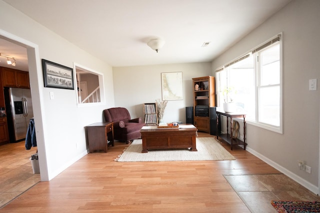 living area with light wood finished floors, visible vents, and baseboards