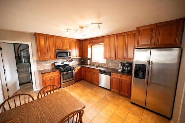 kitchen featuring brown cabinetry, backsplash, stainless steel appliances, and a sink