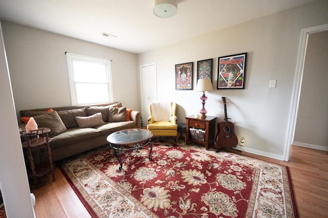 living area featuring visible vents, baseboards, and wood finished floors