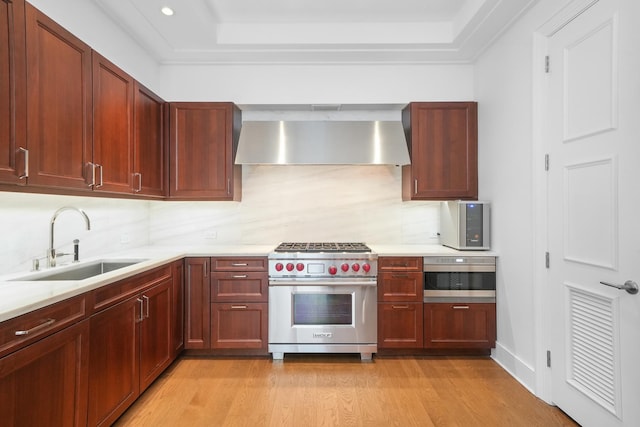 kitchen featuring light countertops, a sink, designer range, and wall chimney exhaust hood