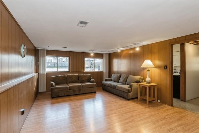 living area with light wood finished floors, wood walls, rail lighting, and visible vents