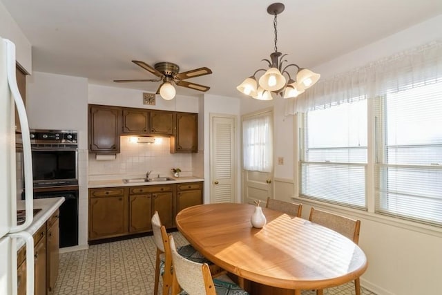 dining space with a healthy amount of sunlight, light floors, and ceiling fan with notable chandelier