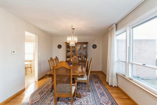 dining room featuring a chandelier, light wood-style flooring, and baseboards