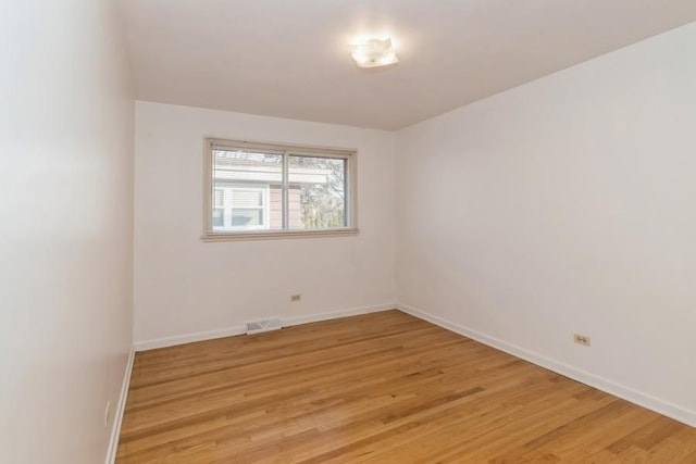 spare room with light wood-style floors, visible vents, and baseboards