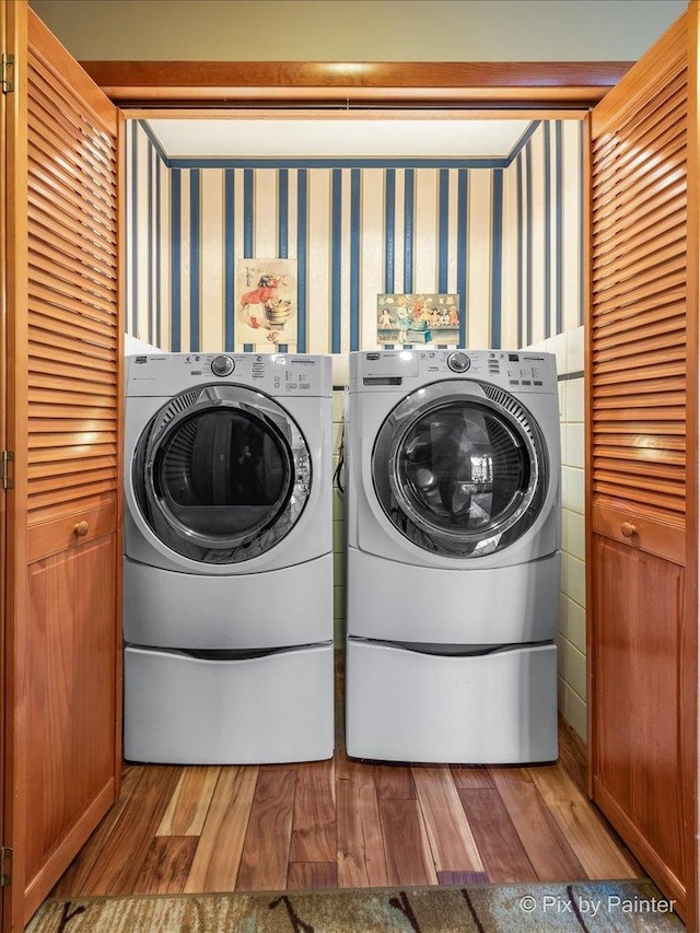 laundry room with laundry area, separate washer and dryer, light wood-type flooring, and wallpapered walls