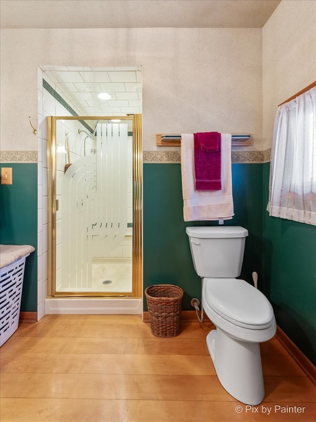 full bathroom featuring a stall shower, toilet, and wood finished floors