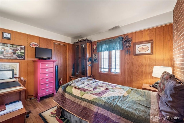 bedroom with hardwood / wood-style floors, wood walls, and a closet