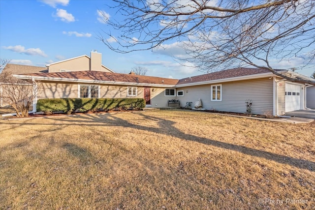 rear view of property with a garage, a lawn, and a chimney