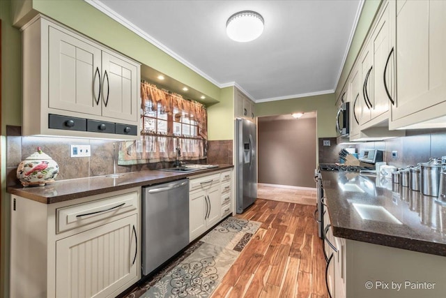 kitchen featuring appliances with stainless steel finishes, backsplash, dark stone counters, light wood finished floors, and crown molding