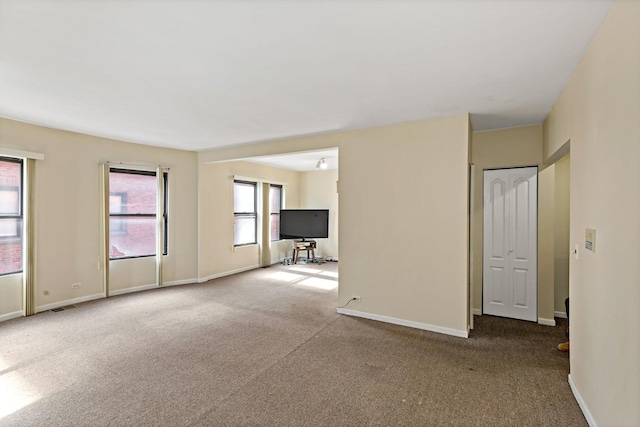 empty room with carpet flooring, visible vents, and baseboards