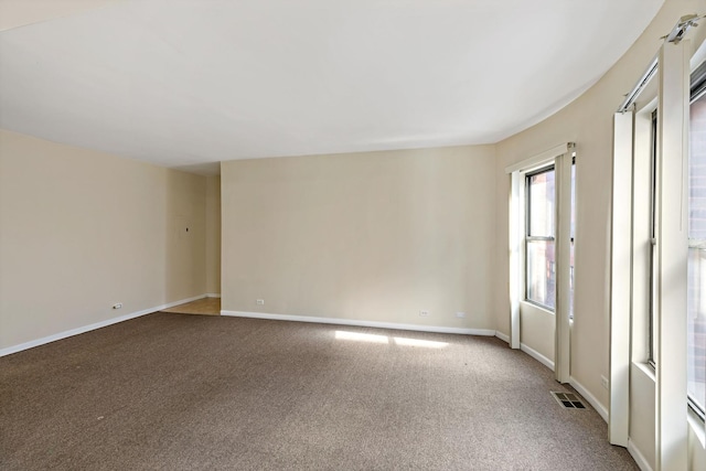 carpeted spare room featuring baseboards and visible vents