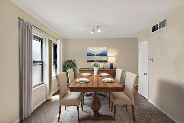 carpeted dining room with visible vents and baseboards