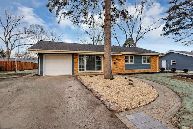 ranch-style home featuring a garage, brick siding, a shingled roof, fence, and driveway