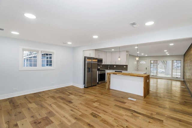 kitchen with stainless steel appliances, visible vents, white cabinets, open floor plan, and decorative light fixtures