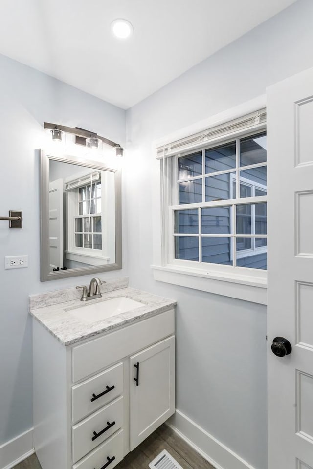 bathroom with wood finished floors, vanity, and baseboards