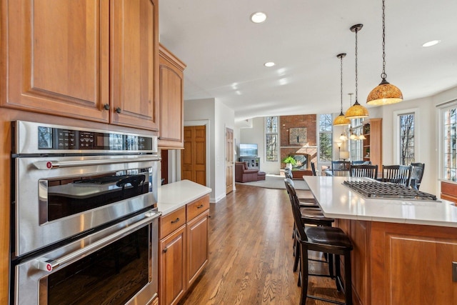 kitchen with double oven, a breakfast bar area, light wood-type flooring, and light countertops