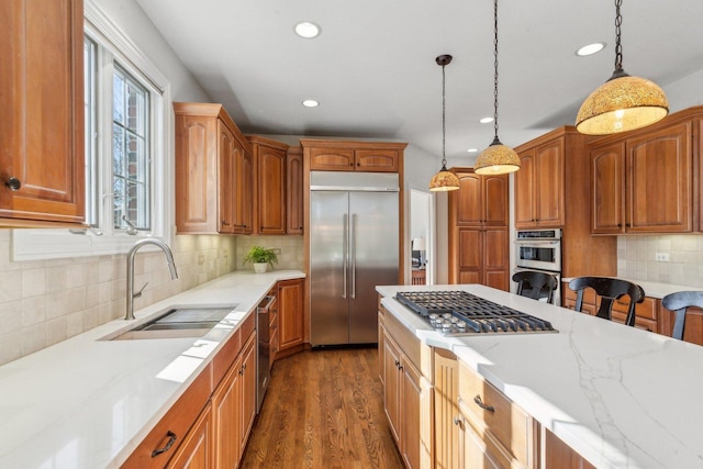 kitchen featuring appliances with stainless steel finishes, decorative light fixtures, a sink, and dark wood-style floors