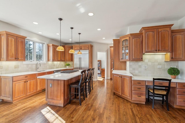 kitchen with built in fridge, a center island, a kitchen bar, and wood finished floors