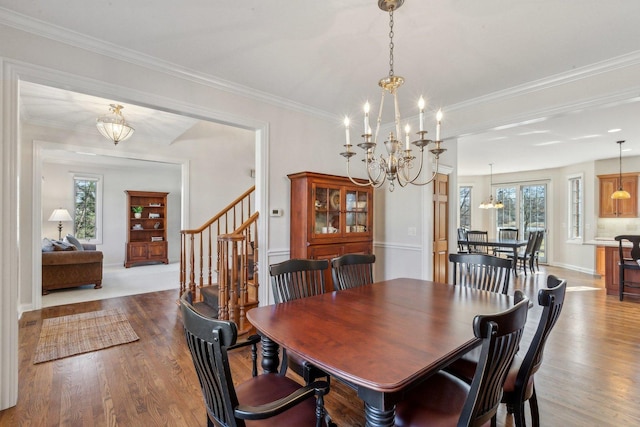 dining area featuring ornamental molding, a healthy amount of sunlight, a notable chandelier, and wood finished floors