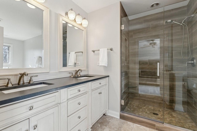 bathroom featuring ceiling fan, a stall shower, a sink, and double vanity