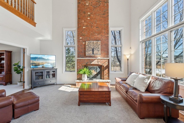 carpeted living area featuring a towering ceiling, a fireplace, and baseboards