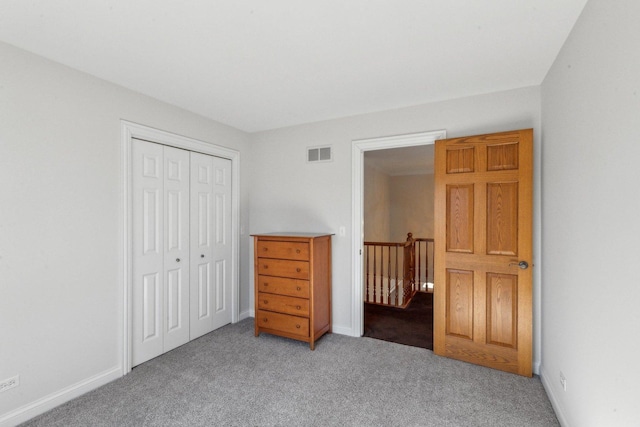 unfurnished bedroom with a closet, visible vents, light carpet, and baseboards