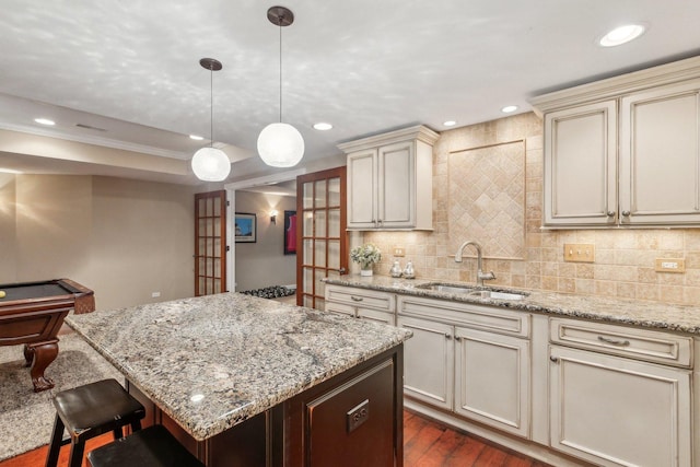 kitchen with a sink, backsplash, cream cabinetry, and recessed lighting