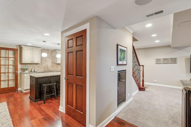 corridor featuring baseboards, visible vents, hardwood / wood-style floors, stairs, and a sink