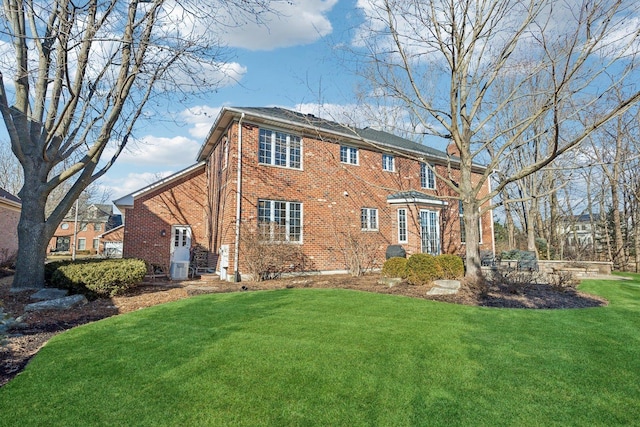 rear view of property featuring a yard and brick siding