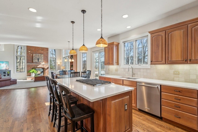 kitchen featuring open floor plan, stainless steel appliances, a kitchen bar, a fireplace, and a sink