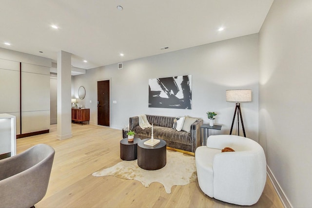 living room featuring decorative columns, baseboards, wood finished floors, and recessed lighting